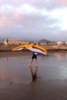 uma homem anda em ao longo a oceano de praia com asa frustrar foto