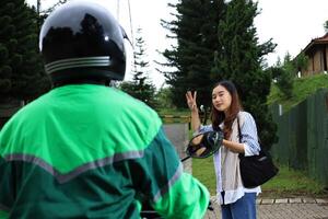 ásia fêmea onda para conectados motorista com moto foto