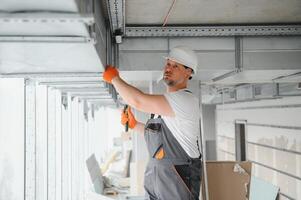 hvac Serviços - trabalhador instalar canalizado tubo sistema para ventilação e ar condicionamento dentro escritório. foto