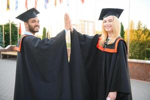 uma multirracial grupo do graduados. indiano masculino graduado e europeu fêmea aluna feliz com diplomas dentro mãos. foto