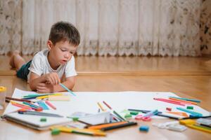 crianças desenhando em chão em papel. pré escola Garoto e menina jogar em chão com educacional brinquedos - blocos, trem, Ferrovia, avião. brinquedos para pré escola e Jardim da infância. crianças às casa ou creche. foto