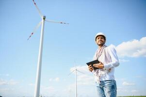 engenheiro Índia homem trabalhando às moinho de vento Fazenda gerando eletricidade limpar \ limpo energia. vento turbina Fazenda gerador de alternativo verde energia. ásia engenheiro verificação ao controle elétrico poder foto