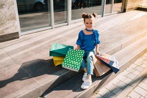 retrato do lindo sorridente pequeno menina vestindo com compras saco ao ar livre foto