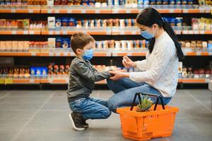 mãe aplica-se desinfetante para limpeza filhos mãos dentro público lotado lugar. compras Shopping foto