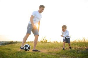 jovem pai com dele pequeno filho jogando futebol, do pai dia. foto