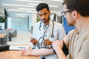 indiano médico segurando discar enquanto medindo do homem sangue pressão foto