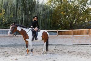 feliz elegante jovem mulher posando com uma cavalo em a de praia foto