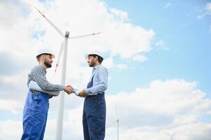 indiano e europeu masculino engenheiros trabalhando em vento Fazenda com moinhos de vento. foto