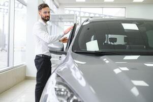 uma homem examina uma carro dentro uma carro concessionária foto