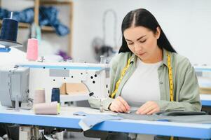 jovem mulher trabalhando Como costureira dentro roupas fábrica. foto