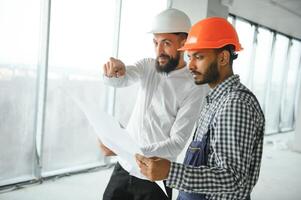 multirracial masculino colegas de trabalho dentro capacetes discutindo projeto em construção local foto