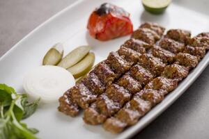 carne seeh Kebab servido dentro prato isolado em cinzento fundo topo Visão do árabe Comida foto