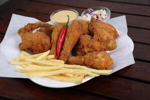 picante frito frango com fritas, maionese mergulho e salada servido dentro uma prato isolado em mesa lado Visão do meio leste Comida foto