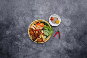 profundo frito frango asas com peixe molho e salada servido dentro tigela isolado em Sombrio cinzento fundo topo Visão do japonês Comida foto