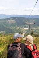 pessoas sentar em a esqui elevador. Visão a partir de a voltar. verão, verde floresta. verão família período de férias dentro a montanhas. foto