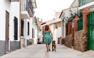 jovem andando na rua com um cão boxer foto