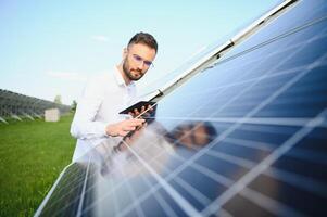 masculino trabalhador solar poder plantar com uma tábua em uma fundo do fotovoltaico painéis. foto