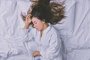 jovem dormindo na cama. vista superior de uma jovem deitada dormindo bem na cama. dormindo, relaxe, jovem sorridente linda senhora encontra-se na cama. relaxando, dormindo. foto