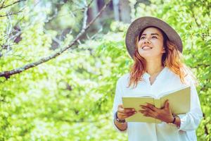 mulher asiática viajar natureza. viajar relaxar. lendo um livro no parque. no verão. foto