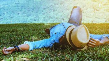 homem asiático viajar relaxar no feriado. durma relaxe no gramado da montanha. no parque público no verão. Na Tailândia foto