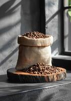 ai gerado café feijões dentro serapilheira saco em de madeira mesa dentro a manhã foto