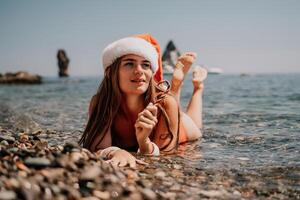 mulher viagem mar. feliz turista apreciar levando cenário em a de praia para recordações. mulher viajante dentro santa chapéu parece às Câmera em a mar baía, partilha viagem aventura viagem foto