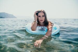 mulher verão mar. feliz mulher natação com inflável rosquinha em a de praia dentro verão ensolarado dia, cercado de vulcânico montanhas. verão período de férias conceito. foto