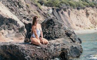 mulher viagem mar. feliz turista dentro branco bikini apreciar levando cenário ao ar livre para recordações. mulher viajante posando em a de praia às mar cercado de vulcânico montanhas, partilha viagem aventura viagem foto