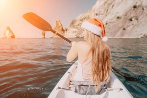 mulher dentro caiaque costas visualizar. feliz jovem mulher dentro santa chapéu flutuando dentro caiaque em calma mar. verão feriado período de férias e alegre fêmea pessoas relaxante tendo Diversão em a barco. foto