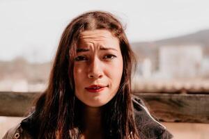 feliz jovem sorridente mulher com sardas ao ar livre retrato. suave ensolarado cores. ao ar livre fechar-se retrato do uma jovem morena mulher e olhando para a Câmera, posando contra outono natureza fundo foto