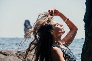 mulher verão viagem mar. feliz turista apreciar levando cenário ao ar livre para recordações. mulher viajante posando em a de praia às mar cercado de vulcânico montanhas, partilha viagem aventura viagem foto