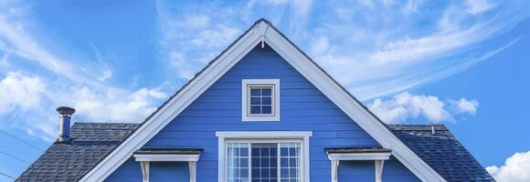 ai gerado a topo cobertura e empena em uma azul casa com branco aparar, contra uma azul céu fundo. foto