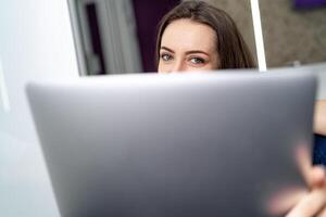 frente Visão do atraente caucasiano menina usando computador portátil. computador portátil em frente Visão com mulher em a fundo. foto