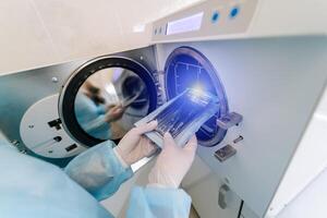 dentista assistente de mãos coloca esterilizando médico instrumentos para a autoclave. seletivo foco foto