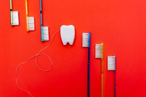 seis dente escovas dentro cru perto brinquedo dente. vermelho fundo. dental conceito. foto