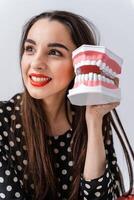 mulher segurando educacional modelo do oral cavidade com dentes em branco fundo. engraçado emoções e expressões. foto