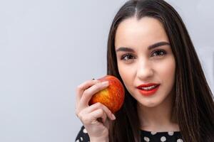 lindo jovem bonita mulher, modelo, menina com vermelho lábios. menina comendo a maçã, sorridente. fechar-se foto