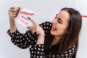 menina colocar dedo para uma dental educacional mandíbula. plástico mandíbula mordidas uma menina de uma dedo. engraçado emoções. foto