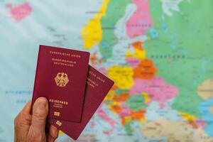 masculino mão com dois alemão passaportes sobre mapa do Europa. foto