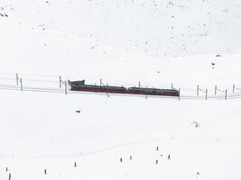 colorida trem em meio a esquiadores dentro Nevado zermatt, Suíça aéreo Visão foto