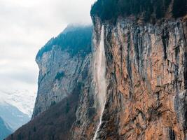 enevoado cascata e áspero falésias dentro Murra, suíça alpino panorama foto