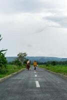 dois hijab ásia mulher equitação bicicleta às a manhã em a asfalto estrada. dois meninas ciclismo com montanha e arroz arroz campo Visão foto