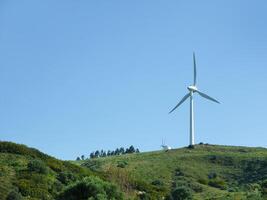 sustentável eco poder energia conceito. moderno vento turbina em verde topo da colina, gerando limpar \ limpo renovável e livre de poluição energia fazenda, moinho de vento gerador foto