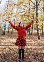 jovem feliz jogando folhas na floresta de outono foto