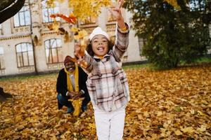 avô e neta negros se divertindo com folhas caídas no parque de outono foto