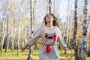 Mulher bonita em roupas de traje tradicional nacional ucraniano dançando na floresta foto