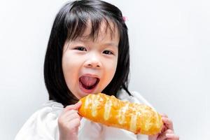menina engraçada comendo pão saboroso com geleia doce. criança olhando para a câmera. em fundo branco isolado.