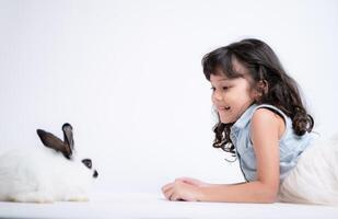 sorridente pequeno menina e com seus Amado fofo coelho, exibindo a beleza do amizade entre humanos e animais foto