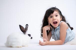 sorridente pequeno menina e com seus Amado coelho, exibindo a beleza do amizade entre humanos e animais foto