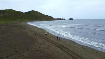 topo Visão do pessoas caminhando em norte costa com montanhas. grampo. lindo andar em oceano costa em nublado dia. pessoas andar de mar com Visão do montanhas e horizonte em nublado dia foto